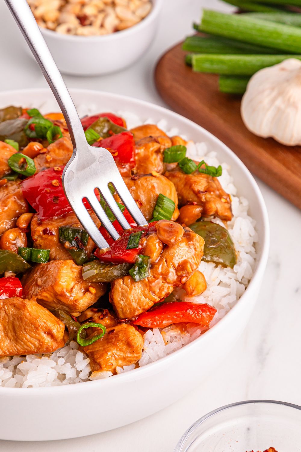 Better Than Takeout Kung Pao Chicken on plate with some rice under, and a fork poking in the chicken 