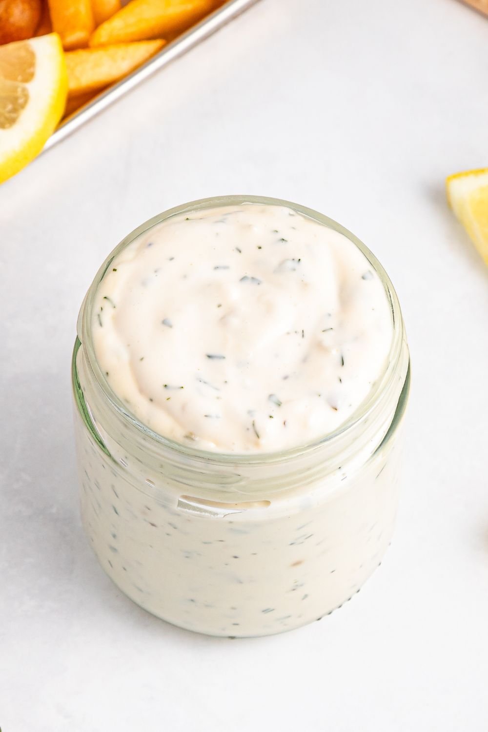 Easy Homemade Tarter Sauce in a glass jar with lemons to side 