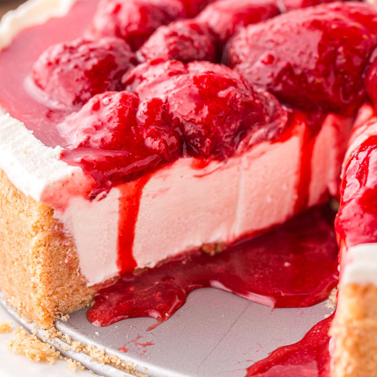 No Bake Strawberry Cheesecake on tray with a slice taken out to see how decadent the cheesecake is 