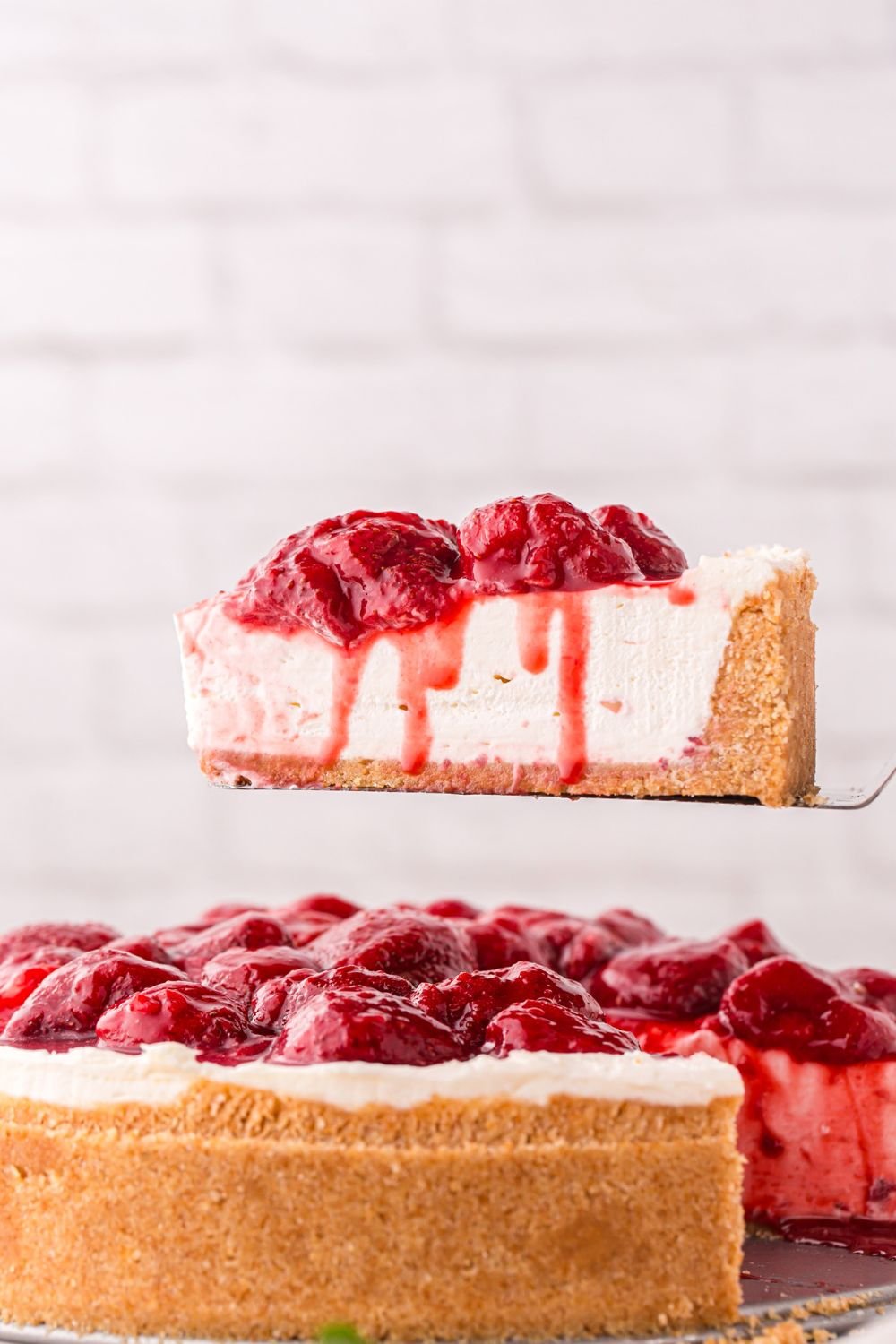 No Bake Strawberry Cheesecake on a spatula being lifted out to show the perfect slice of cheesecake 