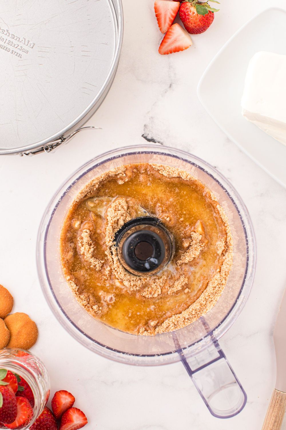 ground up vanilla wafers and butter in a food processor on table