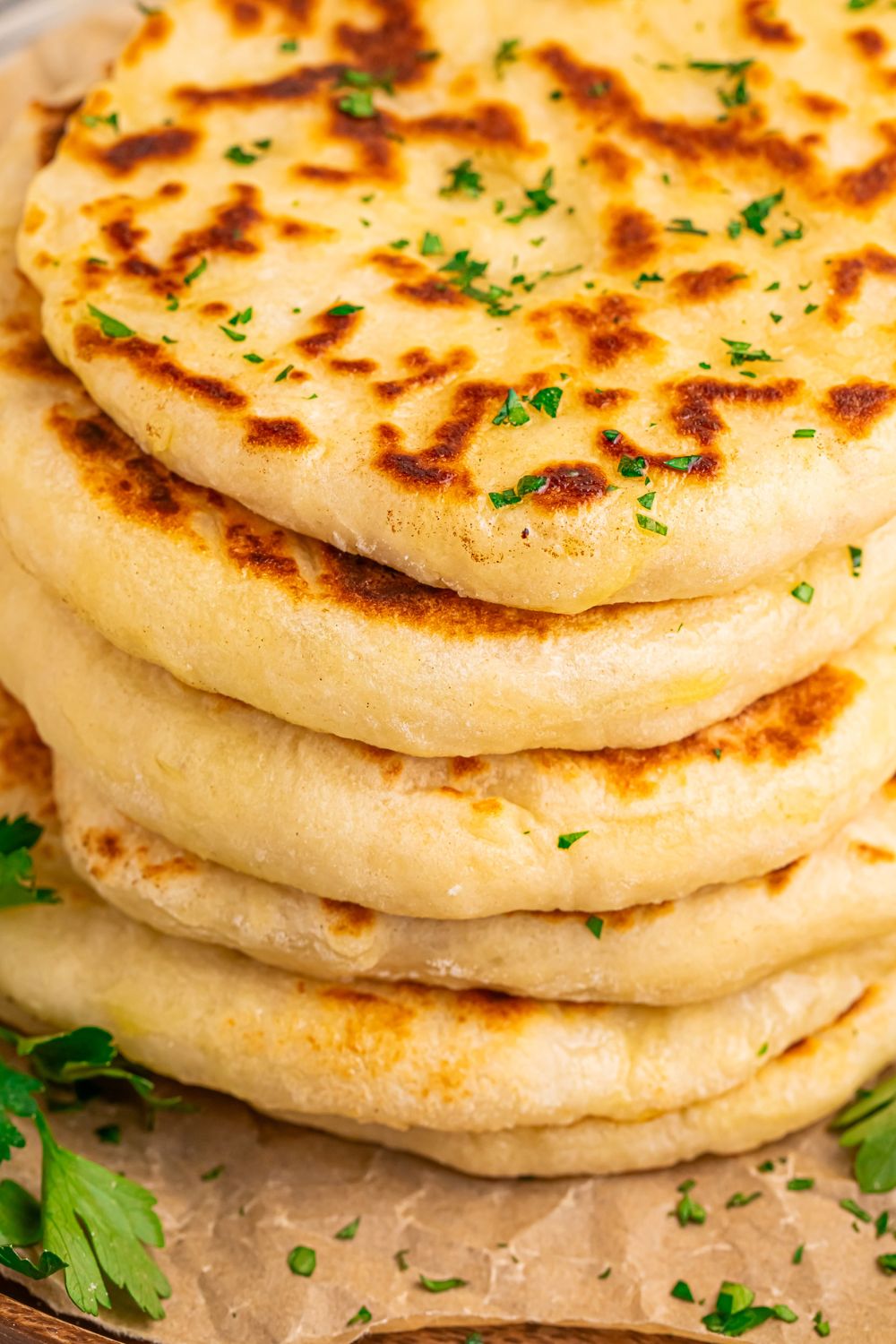 3 Ingredient Flatbread in a stack on a tray with parsley chopped sprinkled around table 