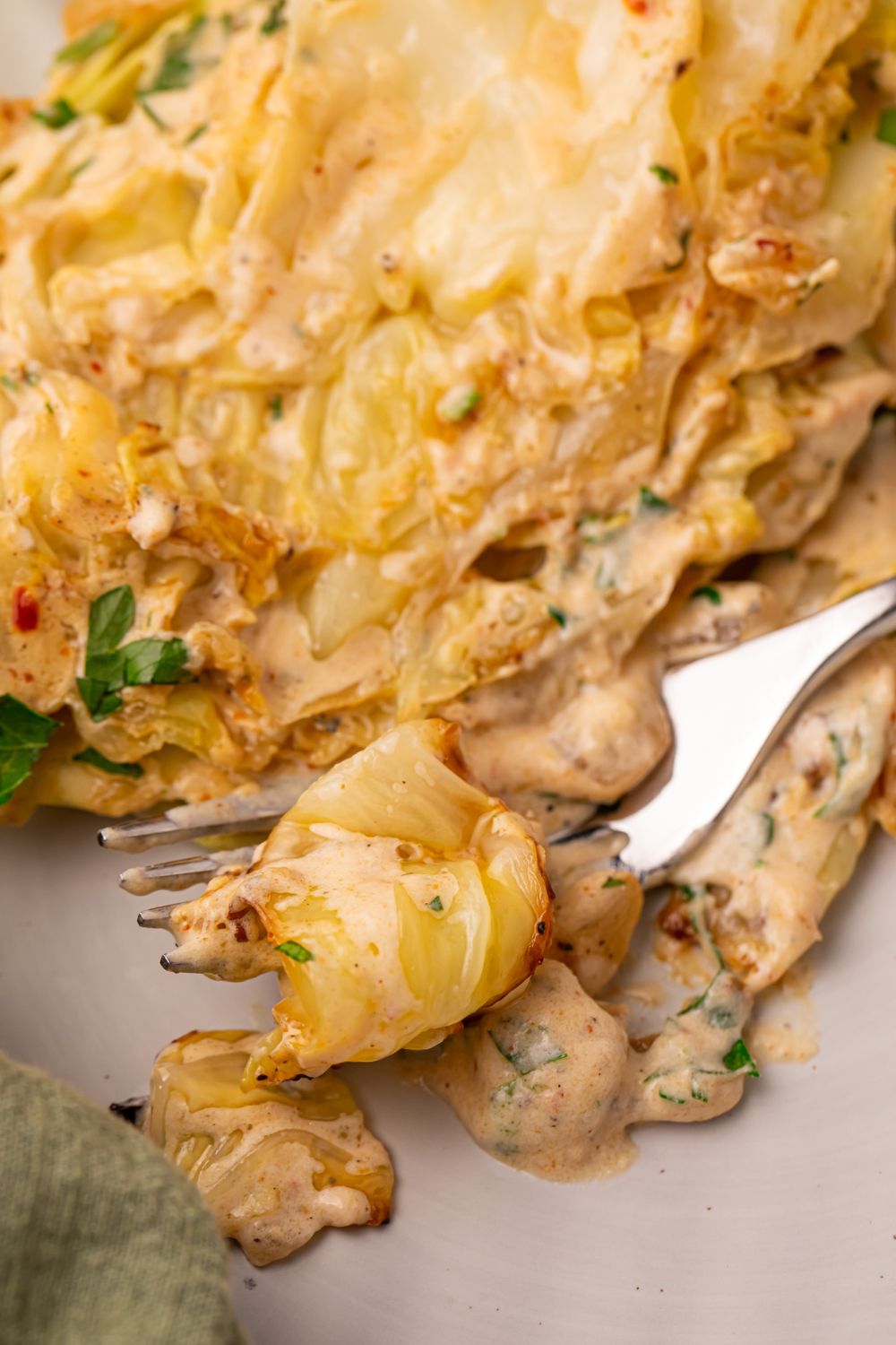 Creamy Garlic Parmesan Cabbage on plate with a fork with some cabbage on it 