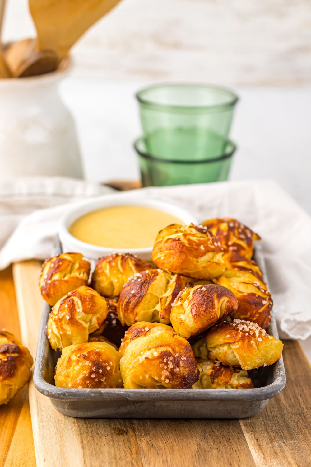 Easy Biscuit Pretzel Bites with Cheese Sauce on table with a towel and glass behind it on table 