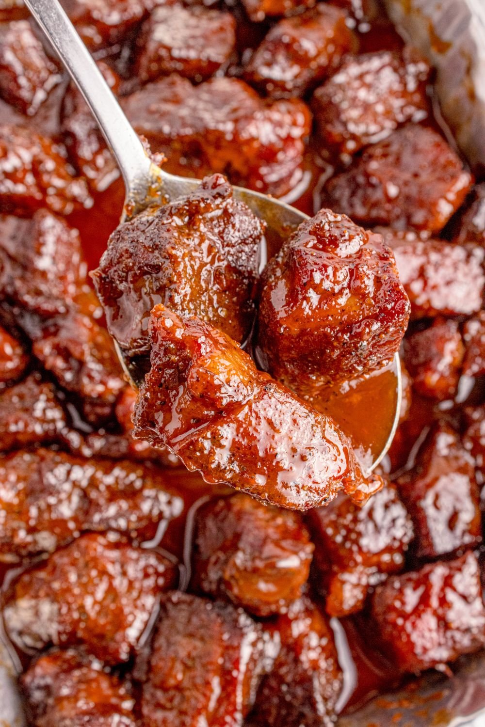 Chuck Roast Burnt Ends in a pan with a spoon scooping some up 