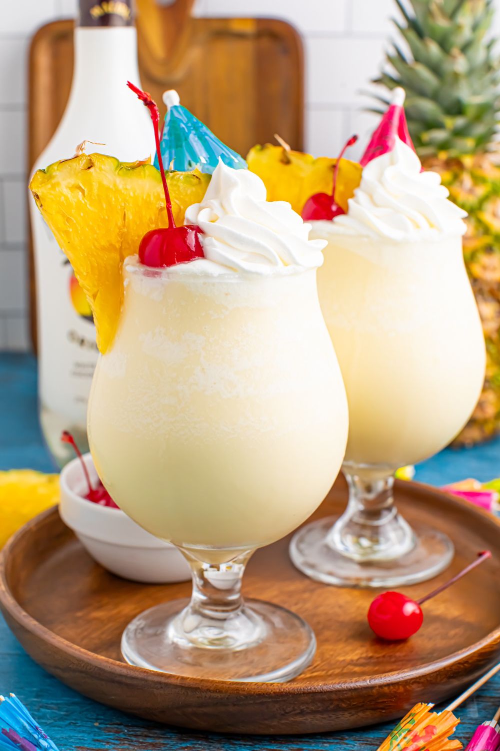 Frozen Malibu Piña Coladas on table with two drinks and a bottle of rum