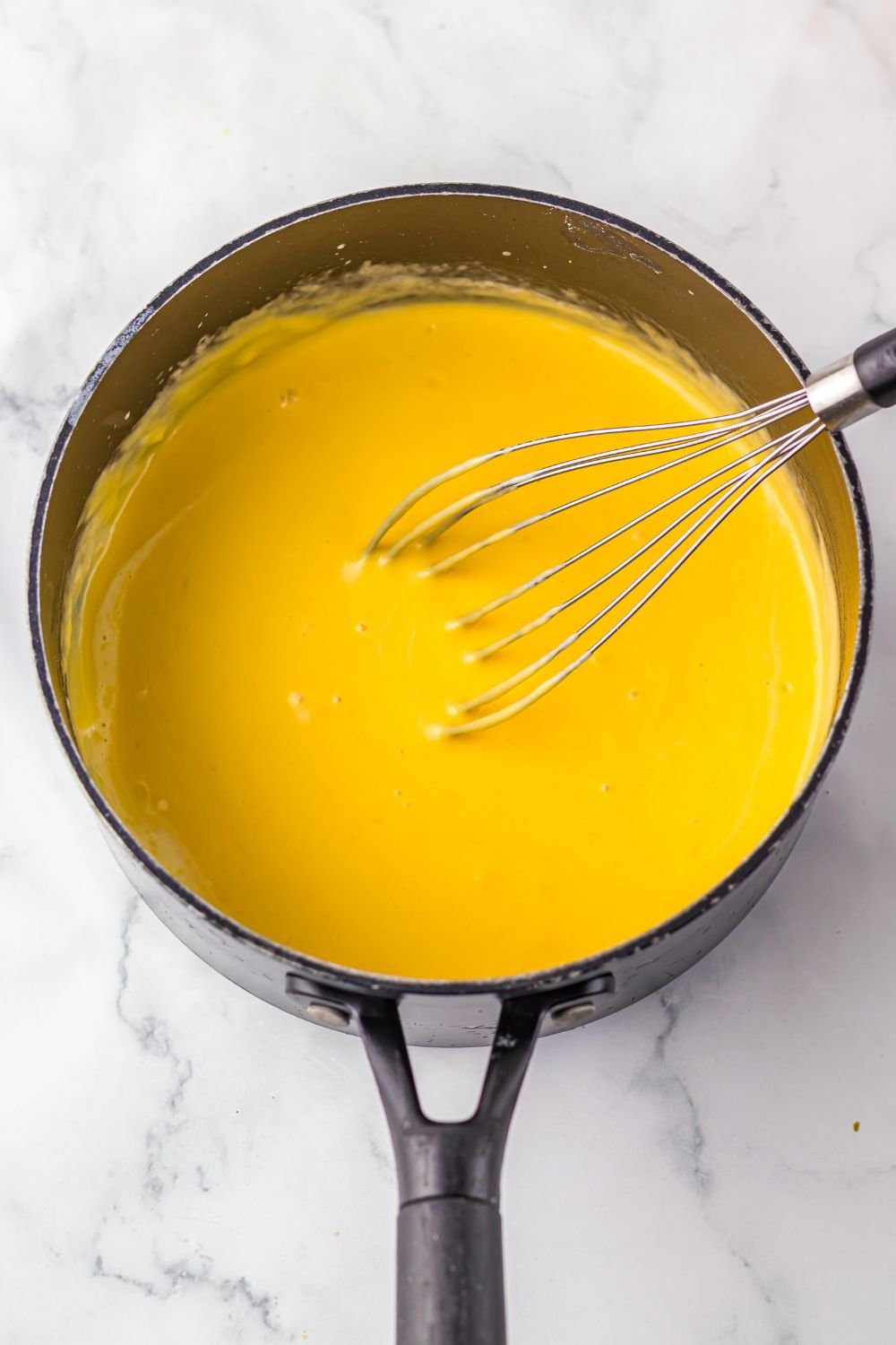 cheese sauce in a sauce pan with a whisk 