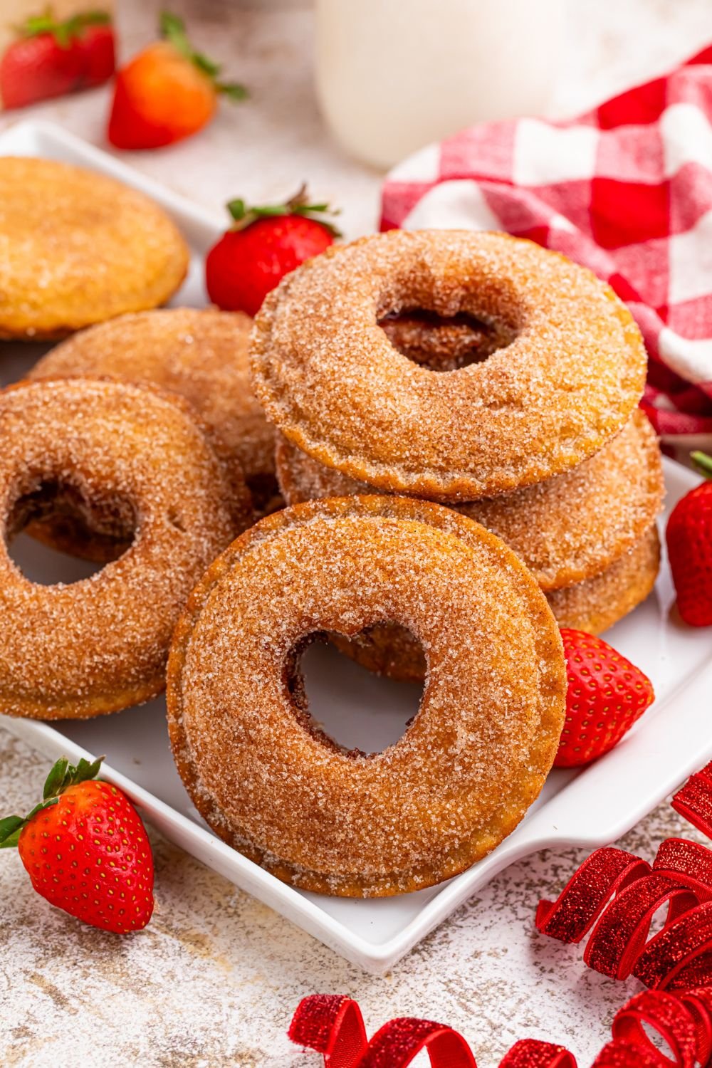 Fried Strawberry Uncrustables with hearts cut out in centers on a tray, and strawberries and other red items around table 