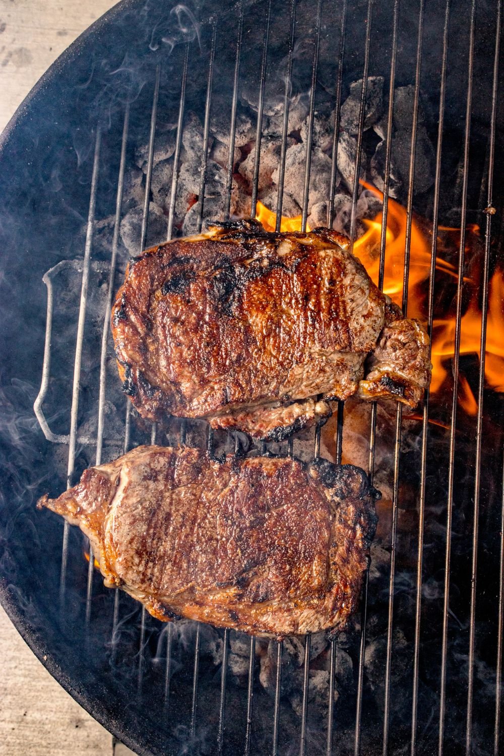 Grilled Ribeye Steaks cooking on a charcoal grill 