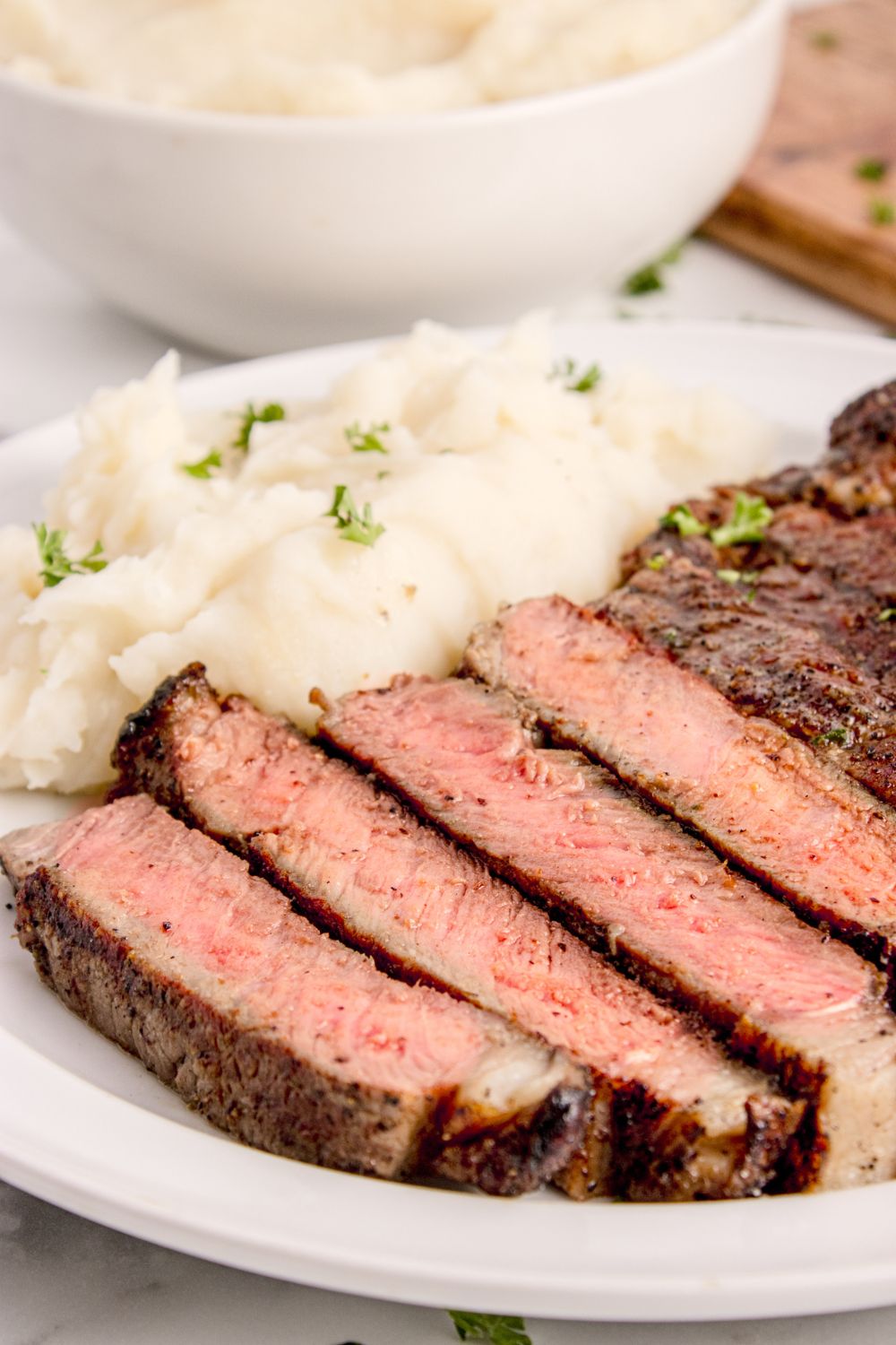 side view of plate with a sliced Grilled Ribeye Steak and potatoes on plate 