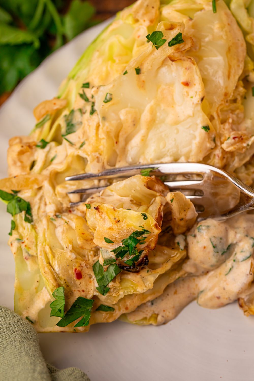 Creamy Garlic Parmesan Cabbage on plate with a fork cutting into a cabbage wedge 