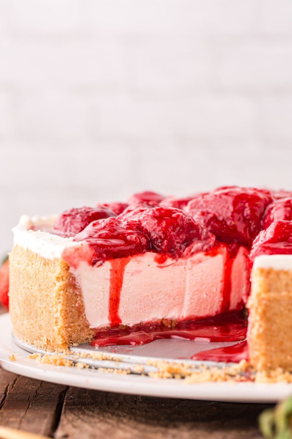 view of strawberry cheesecake on platter with some slices taken out to show how thick the cheesecake is
