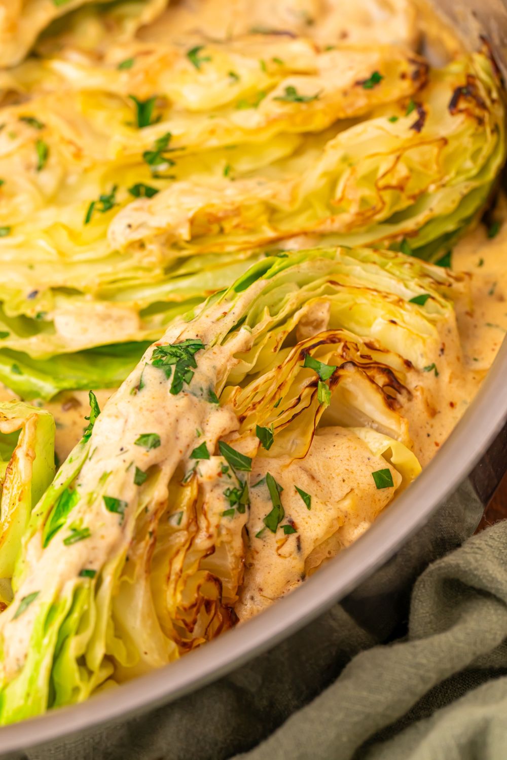 close up of Creamy Garlic Parmesan Cabbage in a skillet with parsley to side 