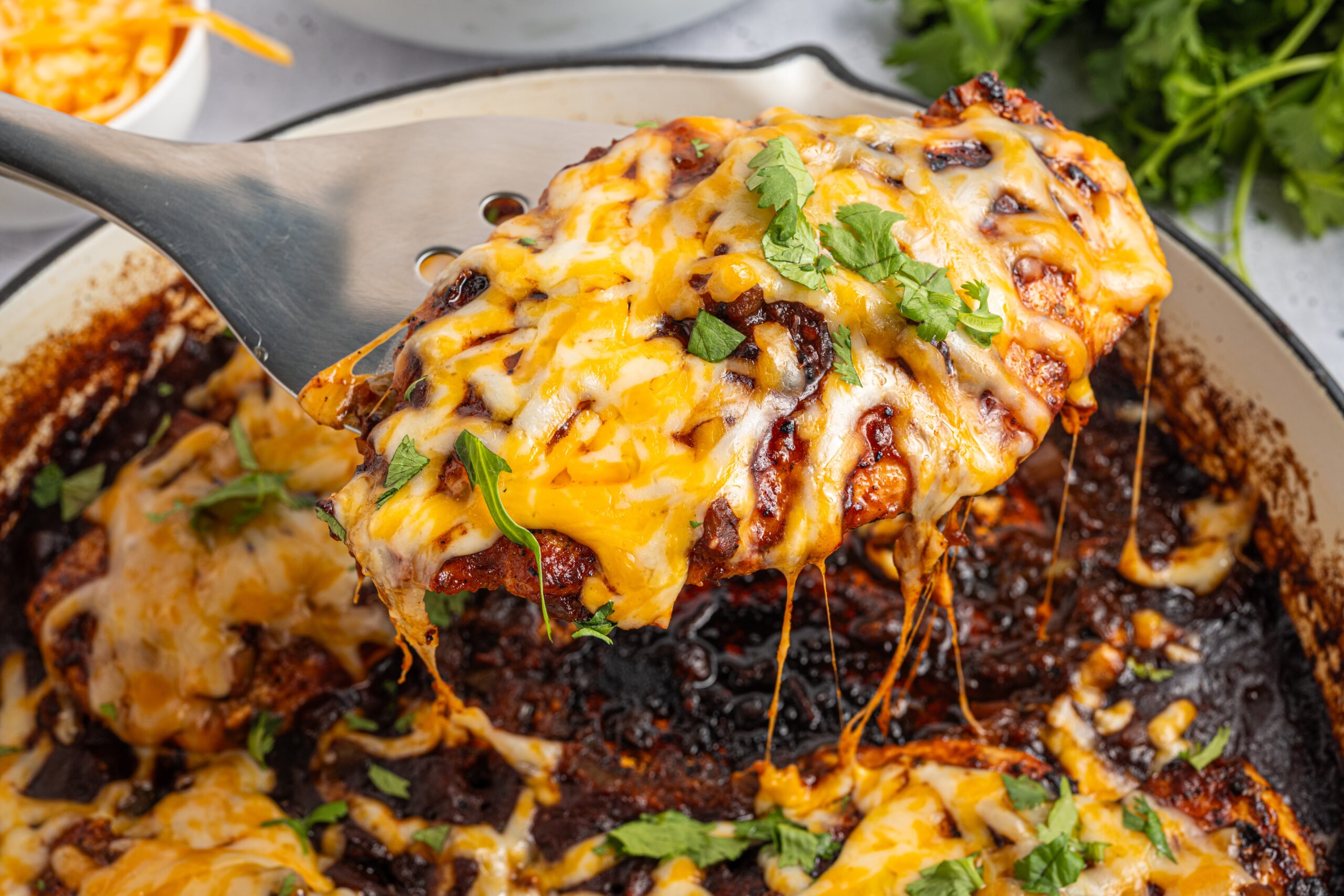 Cheesy Salsa Chicken on pan with a spatula being lifted out of pan 