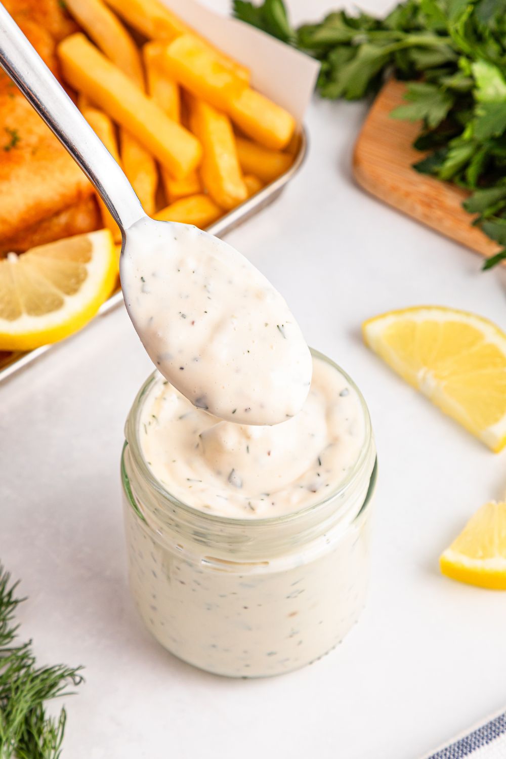 Easy Homemade Tarter Sauce in a jar with some fries and lemon slices to side 