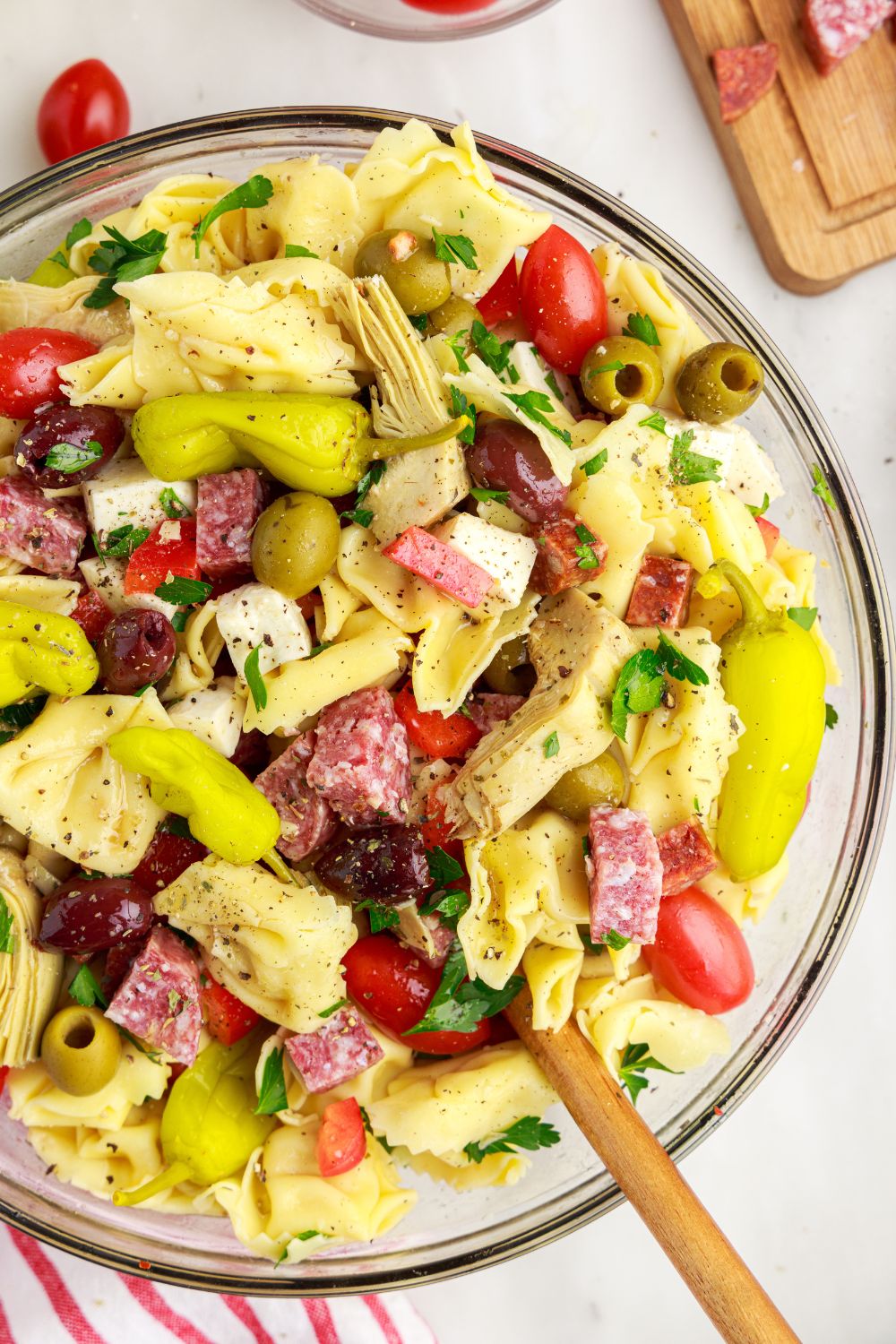 Antipasto Tortellini Pasta Salad on table in a bowl with overhead look of pasta and meat in bowl 