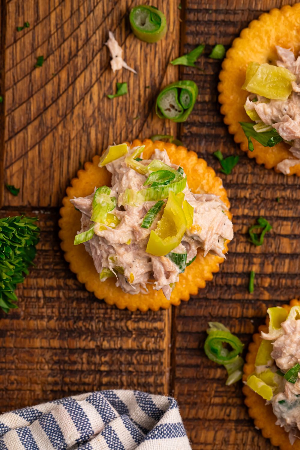 Pepperoncini Ranch Tuna Salad on top of crackers with parsley and green onions on table 