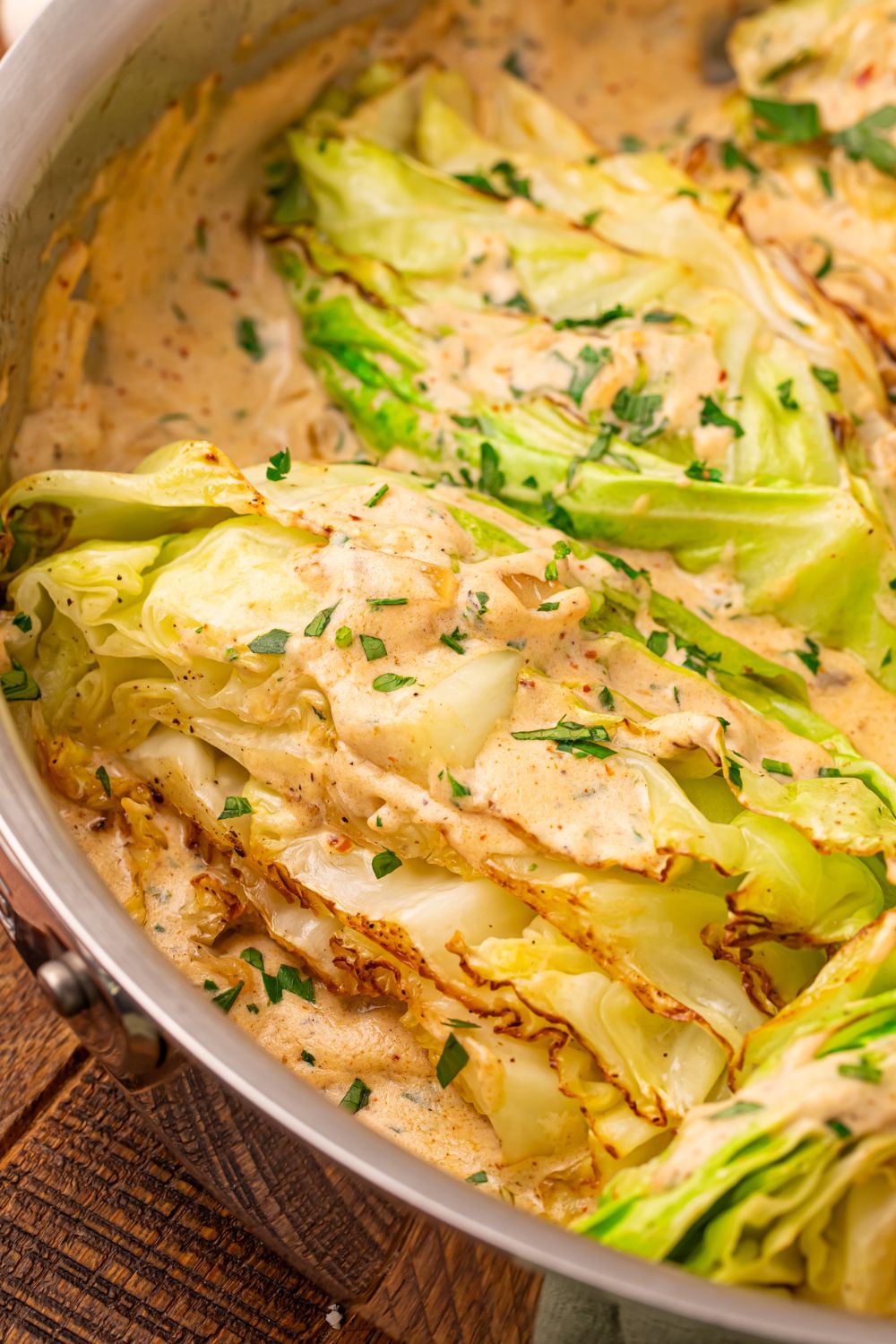 Creamy Garlic Parmesan Cabbage in a skillet with a close up look at the sauteed cabbage 