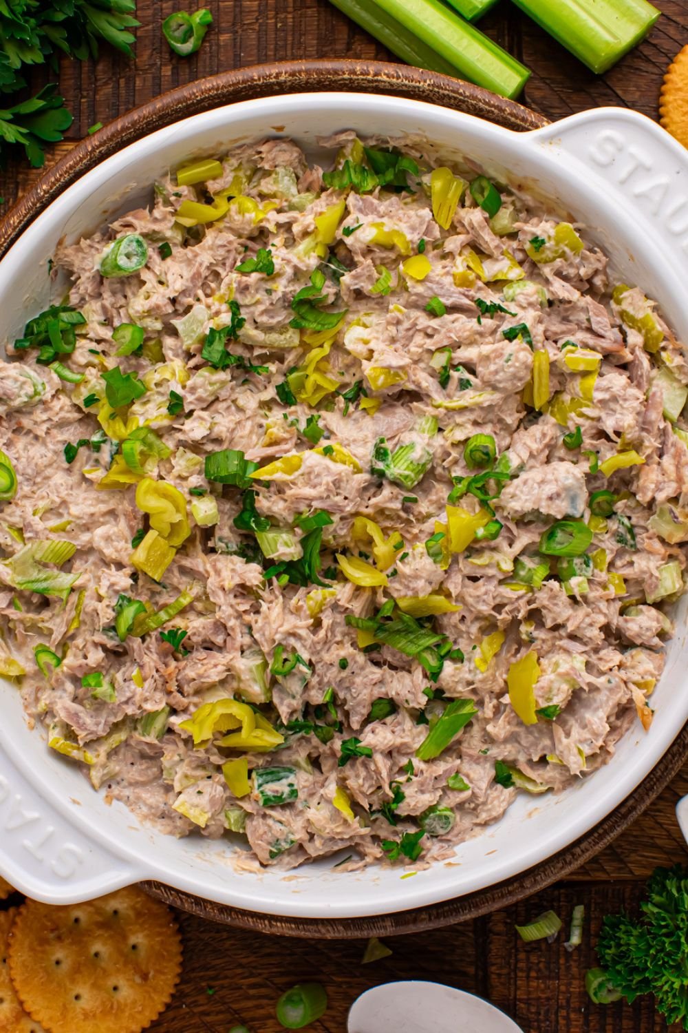 overhead look of a large bowl of Pepperoncini Ranch Tuna Salad on table with some celery to side and fresh parsley bundle 