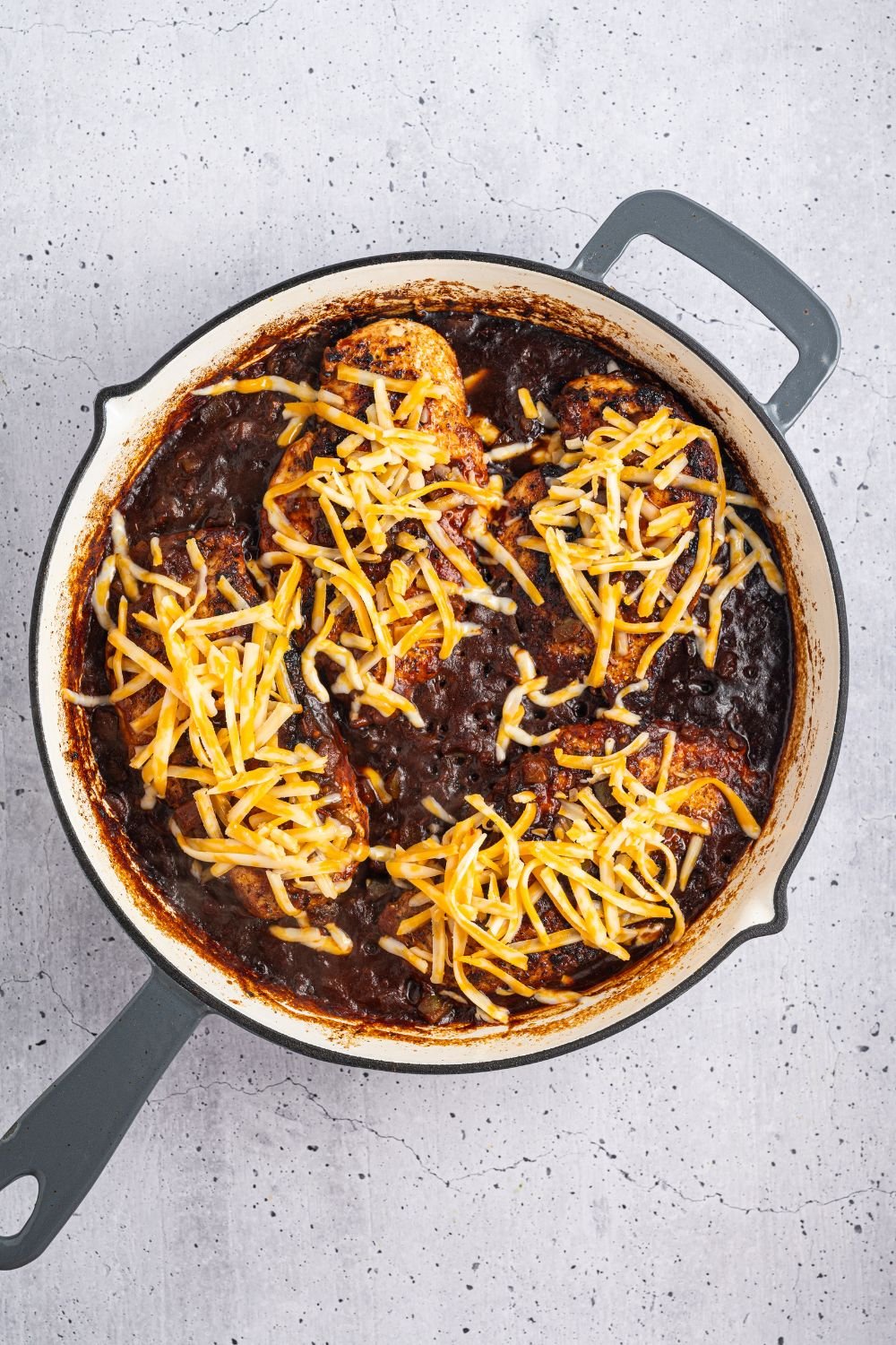saucy Cheesy Salsa Chicken in a skillet with cheese sprinkled on top 