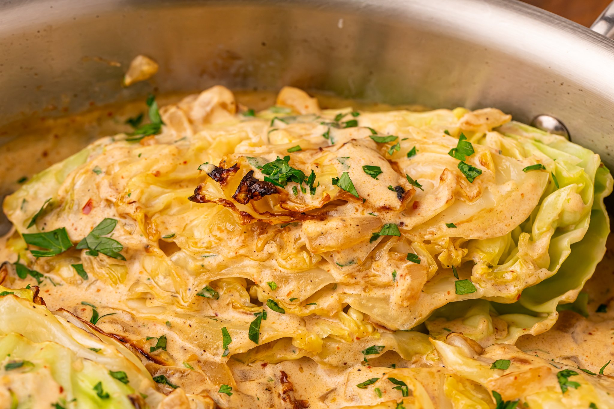Creamy Garlic Parmesan Cabbage wedge in the skillet topped with some parsley 