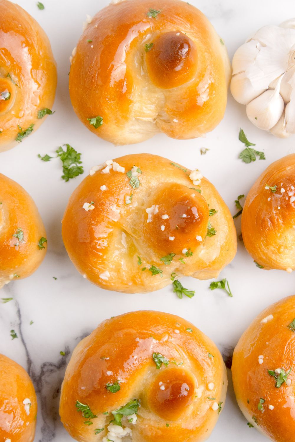 Homemade Garlic Knots spread out on table all brushed with butter and parsley