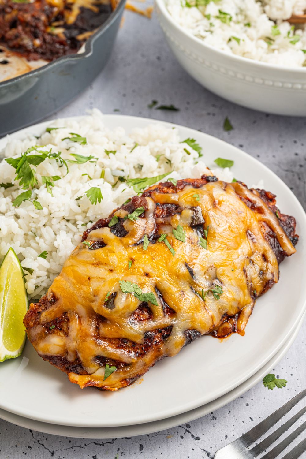 Cheesy Salsa Chicken on a plate with rice and parsley with lime slice 