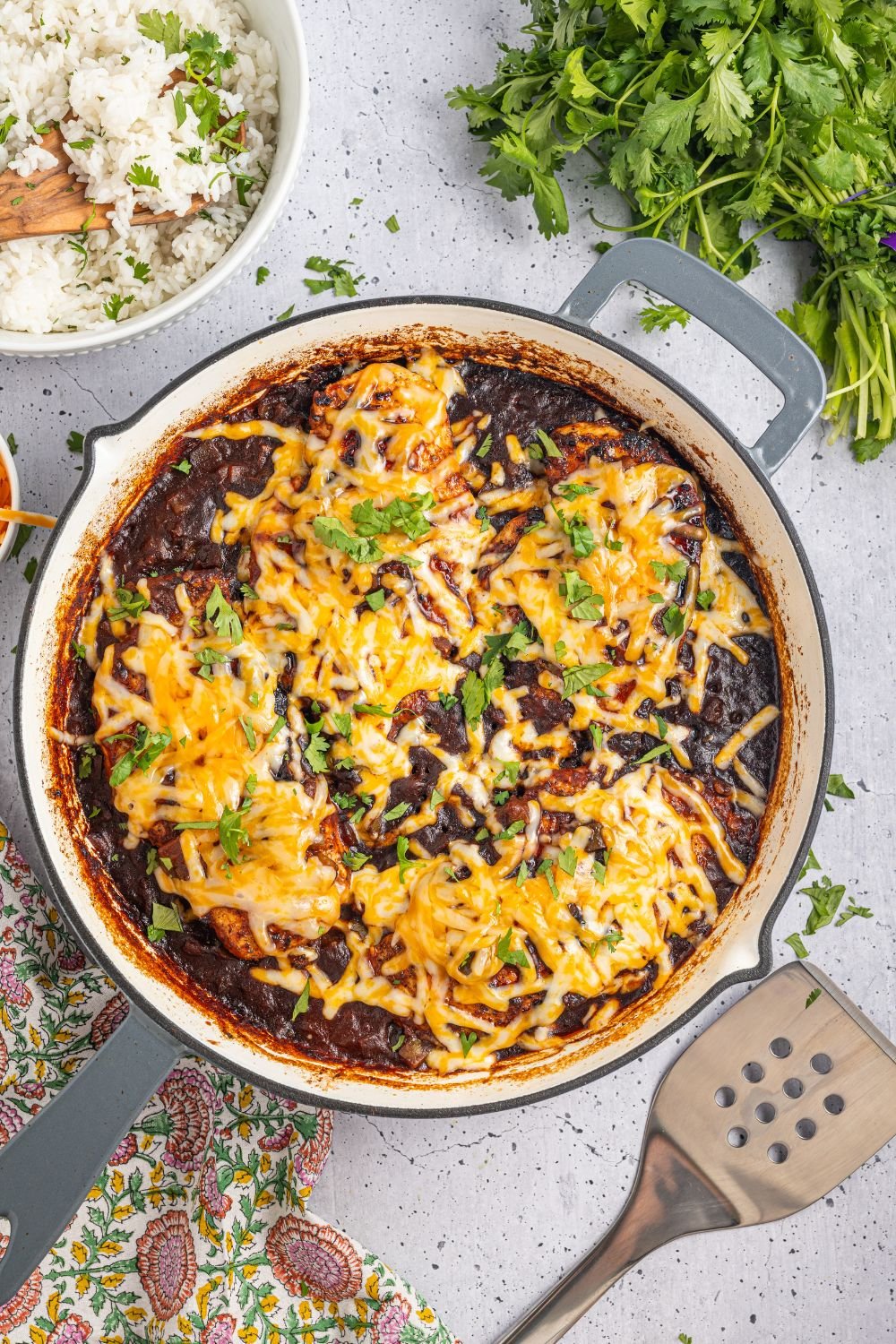 overhead look of Cheesy Salsa Chicken with a spatula to side and parsley to side and rice in a bowl 