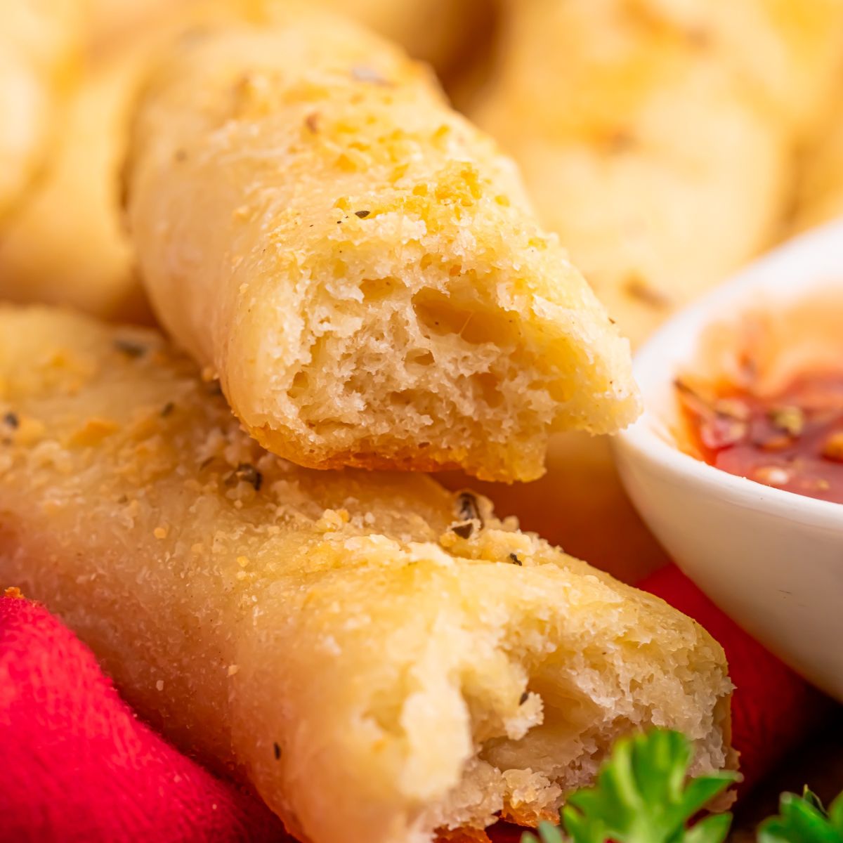2 Ingredient Garlic Parmesan Breadsticks on table with one torn in half 