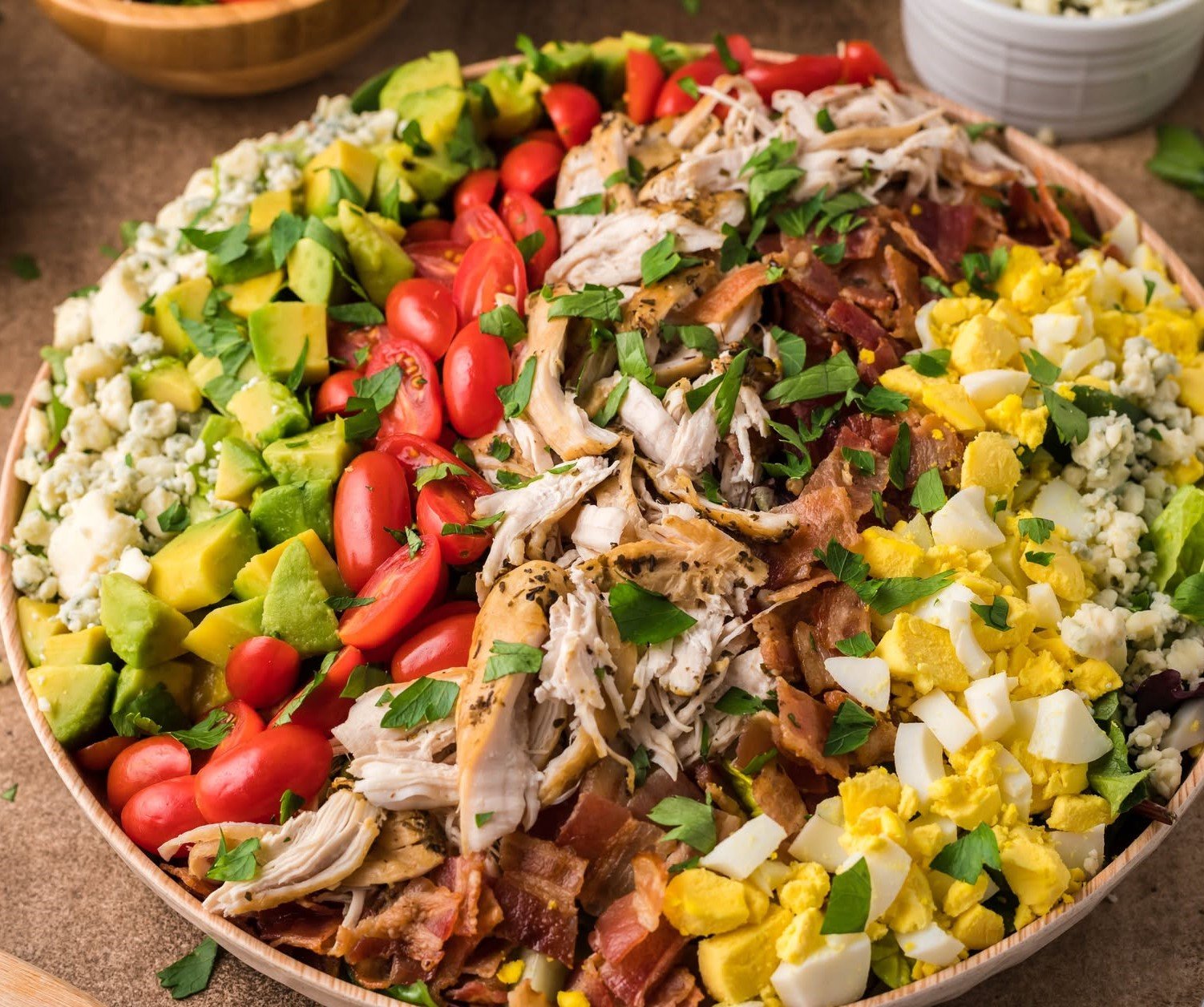 Copycat Cheesecake Factory Cobb Salad in a large wooden serving bowl on a table 