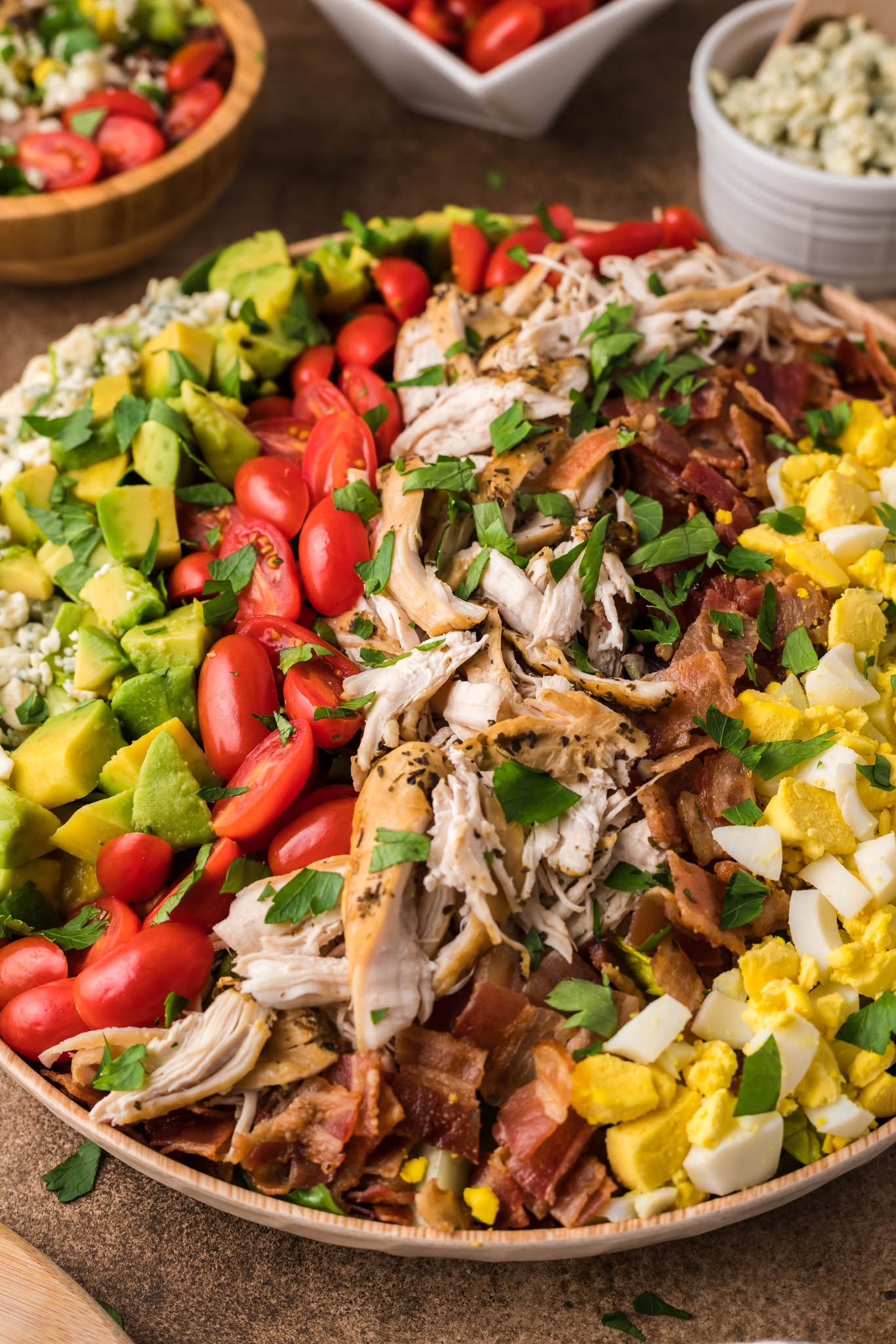 Copycat Cheesecake Factory Cobb Salad in a large wooden serving bowl on a table 
