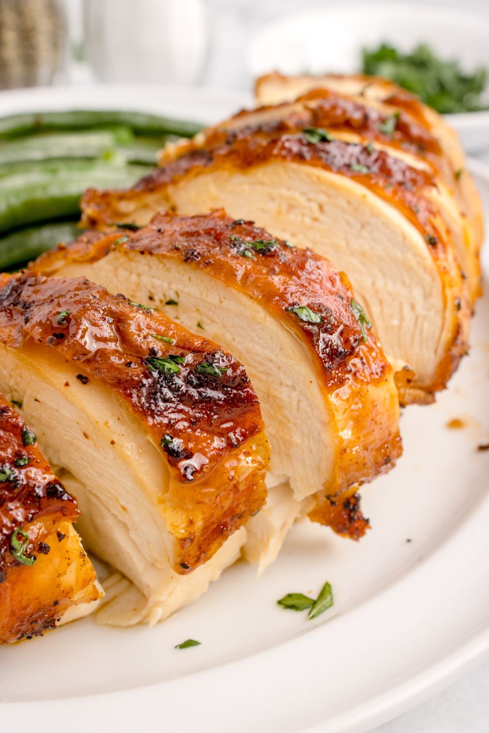 Air Fryer Chicken Breast sliced and placed on a plate with some vegetables to side of plate 