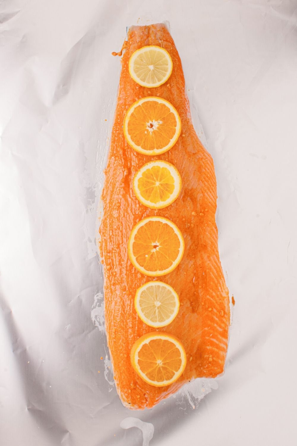 raw salmon with sauce spread on top and orange slices 