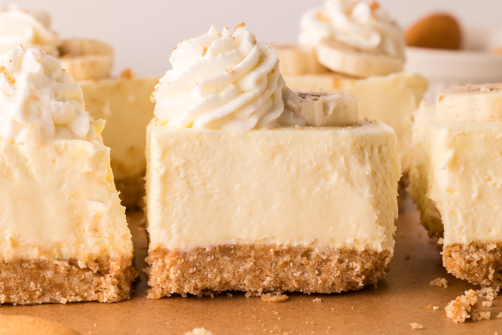 No Bake Banana Pudding Cheesecake Bars lined up on a wooden cutting board 