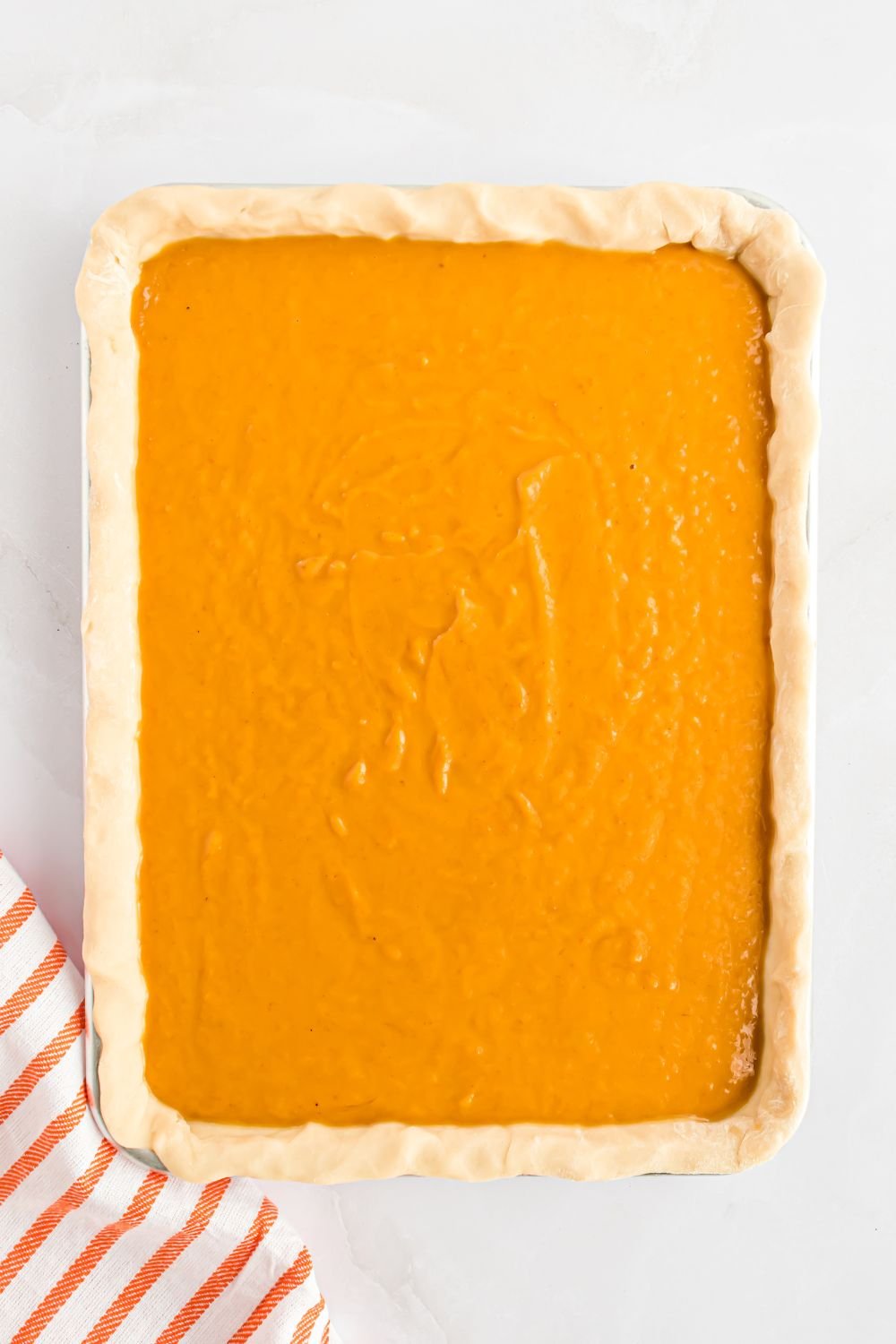 overhead look down on table with a sheet pan with raw pumpkin pie in a metal sheet pan on table 