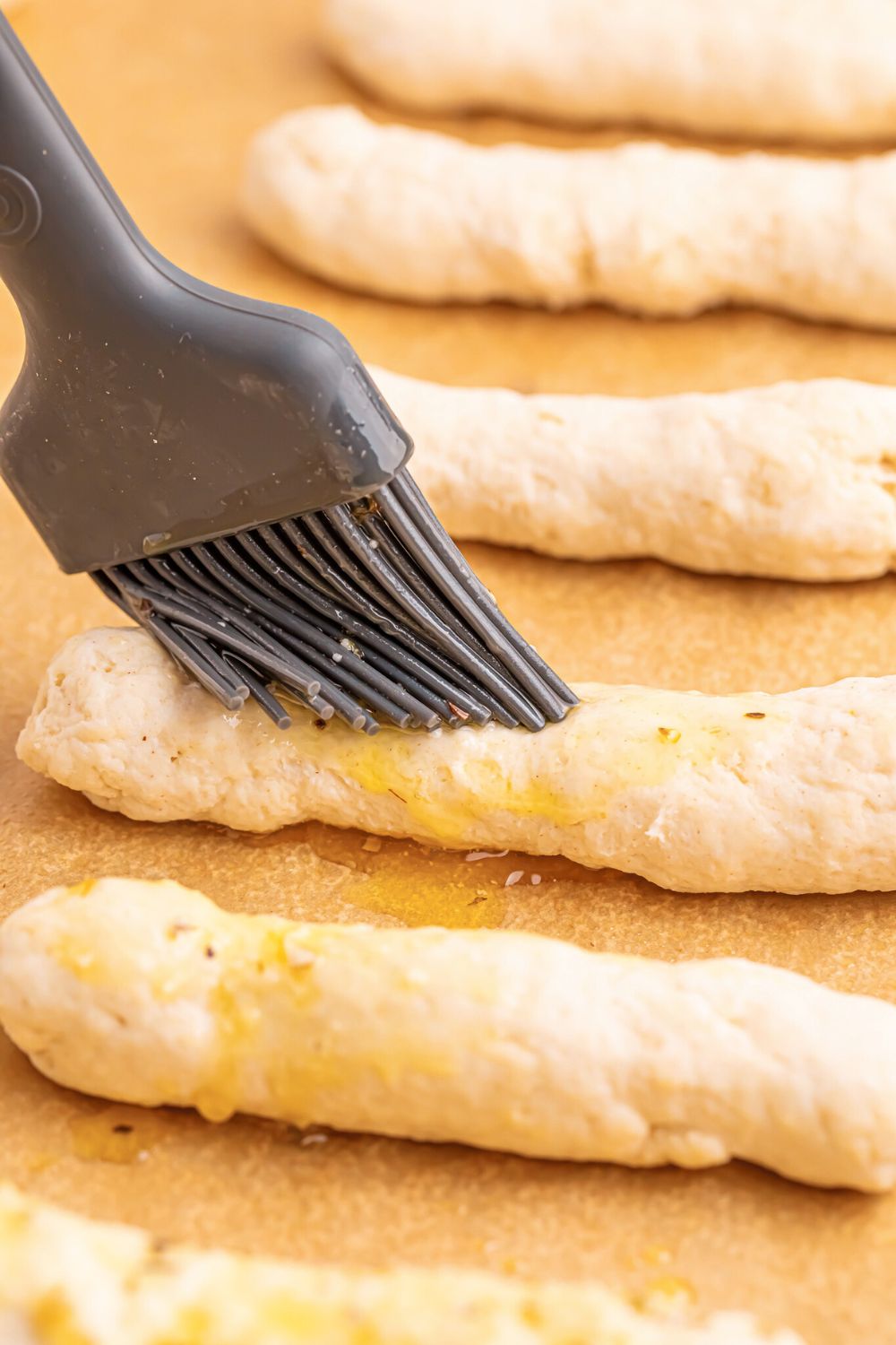 brushing raw 2 Ingredient Garlic Parmesan Breadsticks with butter 