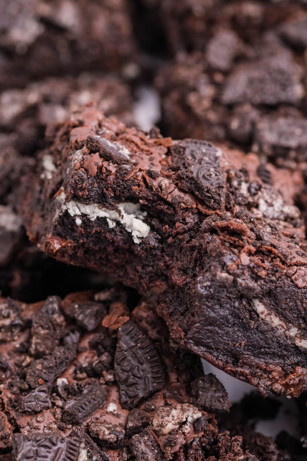 Oreo Stuffed Brownies stacked on table with one that has a bit taken out of it 