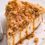 Caramel Apple Crisp Cheesecake sliced and placed on a plate with a fork to the side