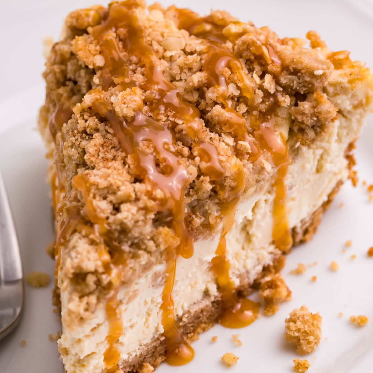 Caramel Apple Crisp Cheesecake sliced and placed on a plate with a fork to the side 