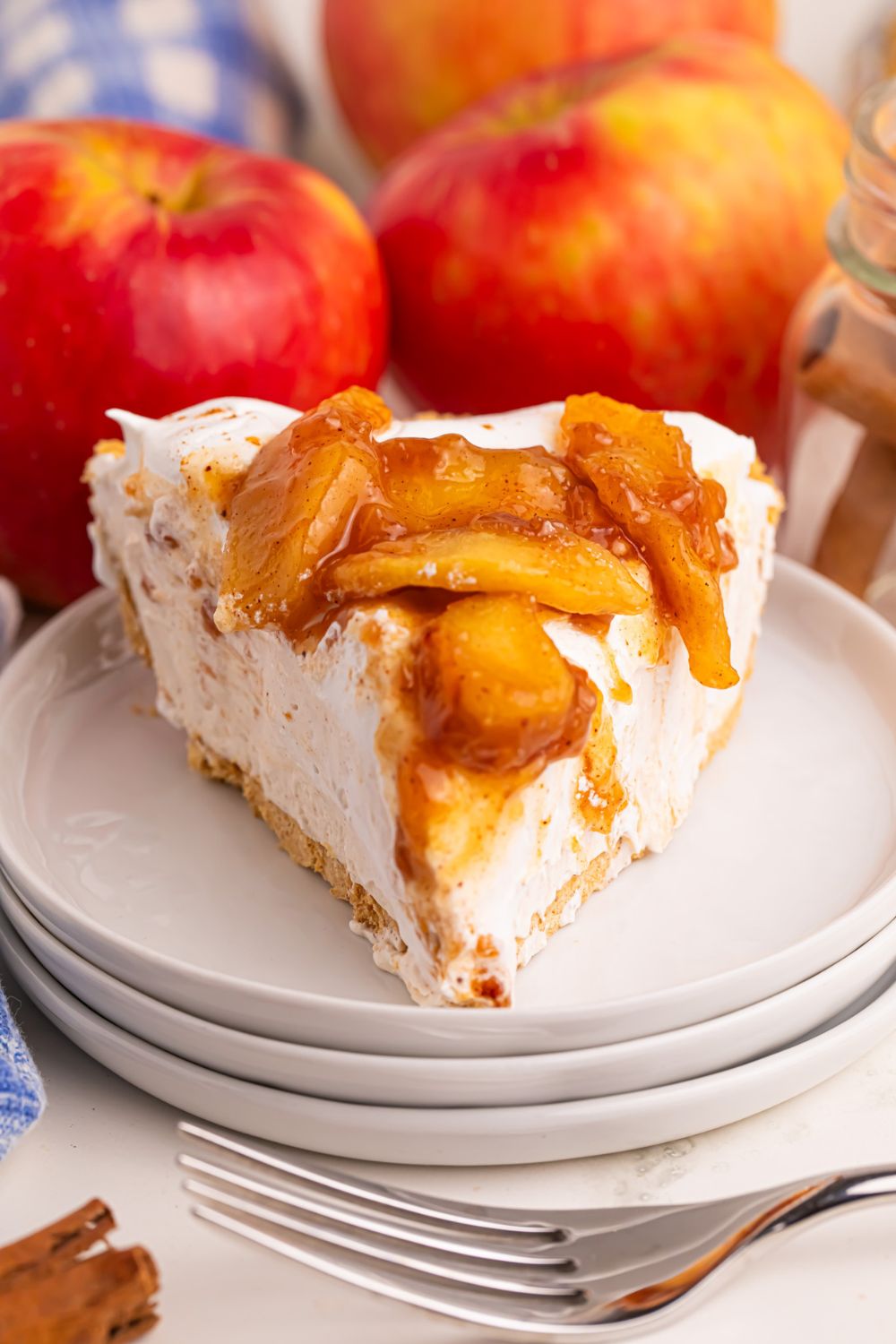 No Bake Apple Cheesecake pie on plates with fresh apples behind it on table 