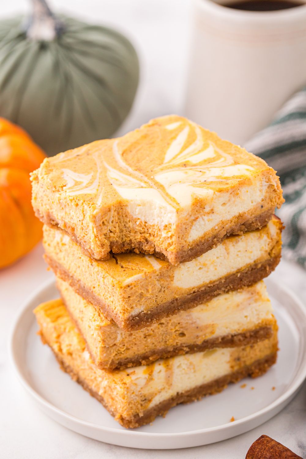 Swirled Pumpkin Cheesecake Bars stacked on plate with a bite taken out of it