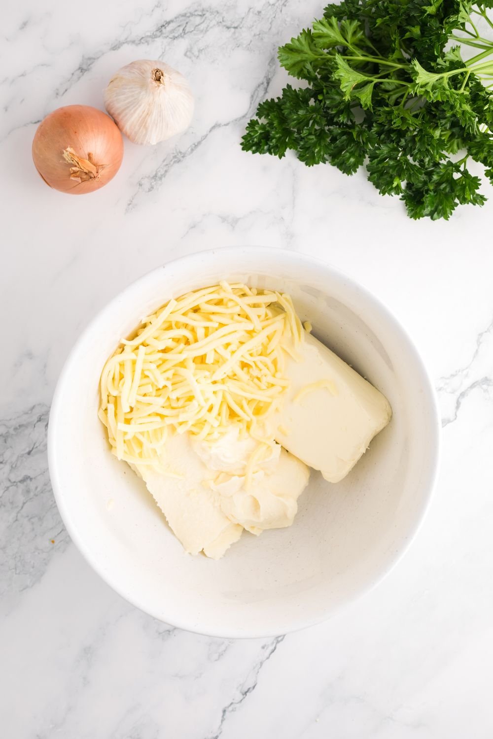 cream cheese and shredded cheese in a glass bowl