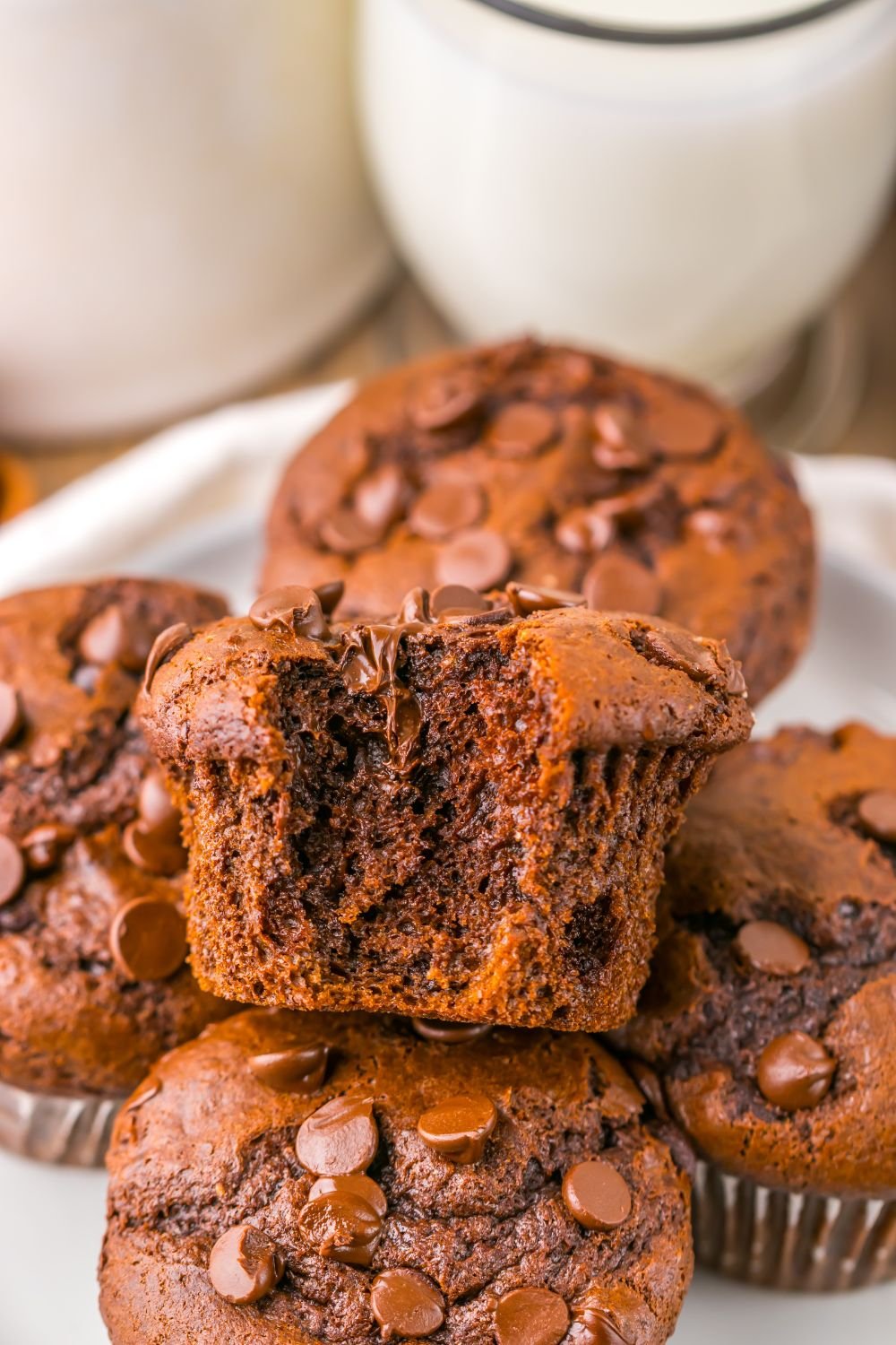 Costco Double Chocolate Muffins stacked on plate with a bite taken out of the top muffin on pile
