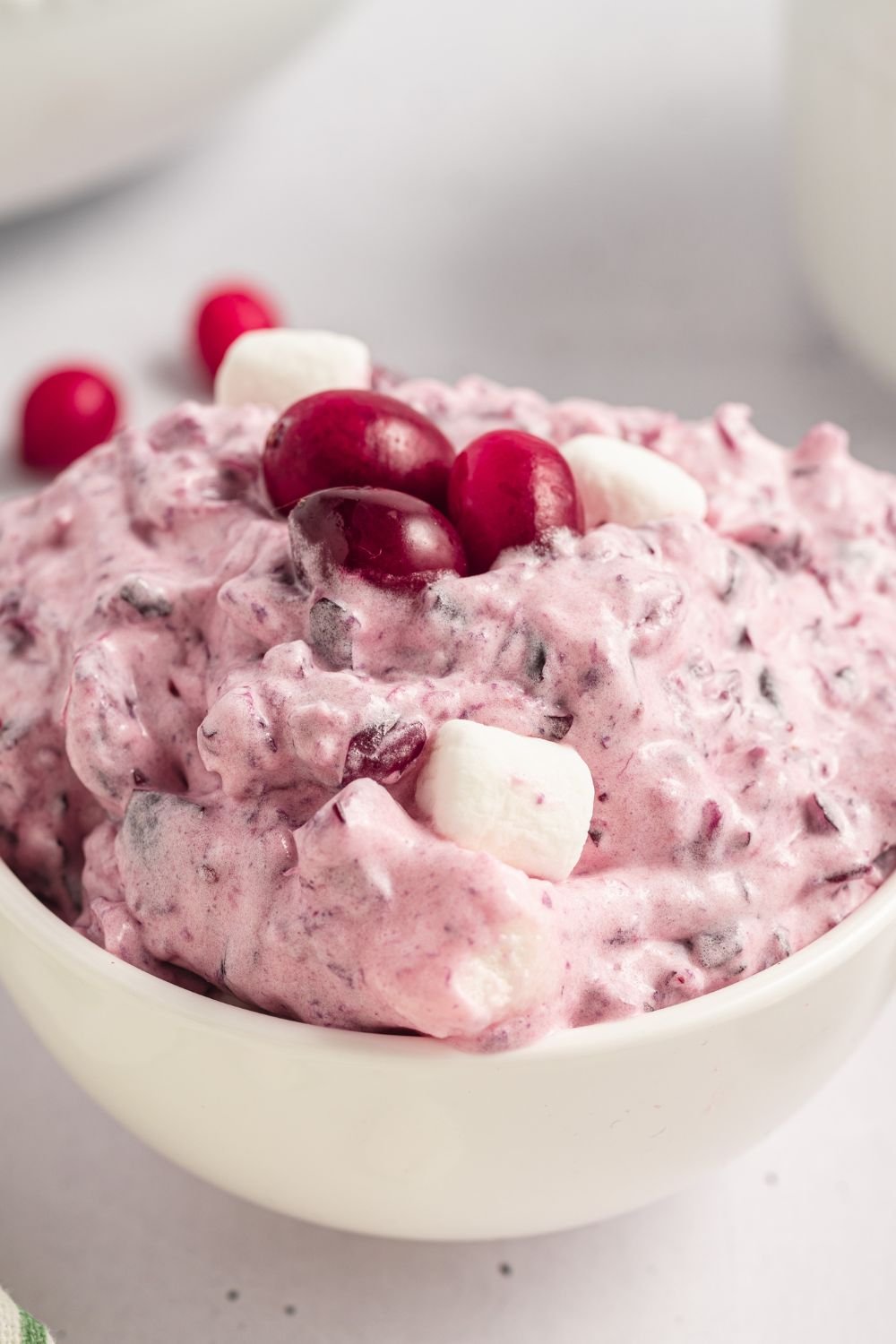 small white bowl full of Cranberry Fluff Salad with a few fresh cranberries 