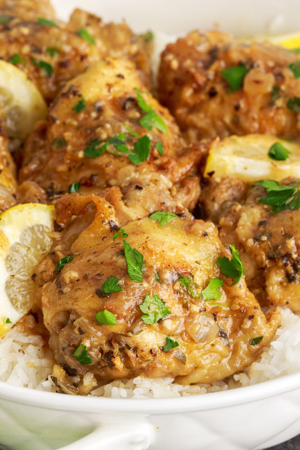 close up of Instant Pot Lemon Butter Chicken on plate with some rice under the chicken pieces 