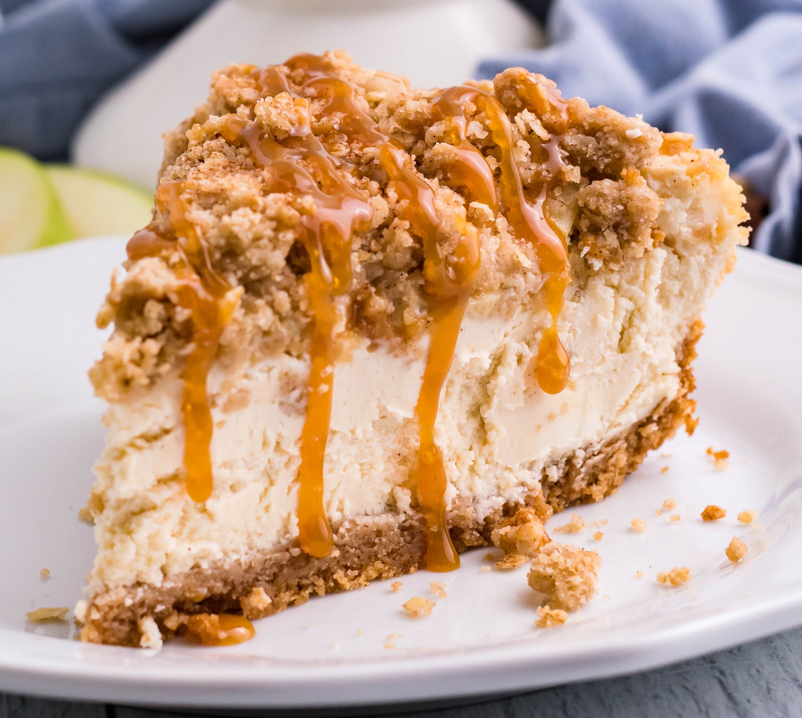 slice of Caramel Apple Crisp Cheesecake on plate drizzled with caramel