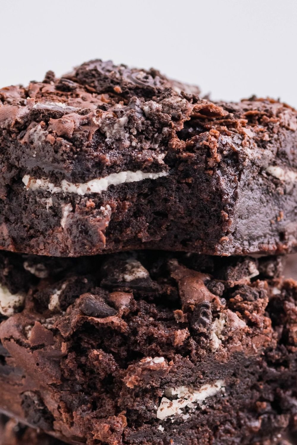 stack of Oreo Stuffed Brownies on table showing the cookies on top of each brownie