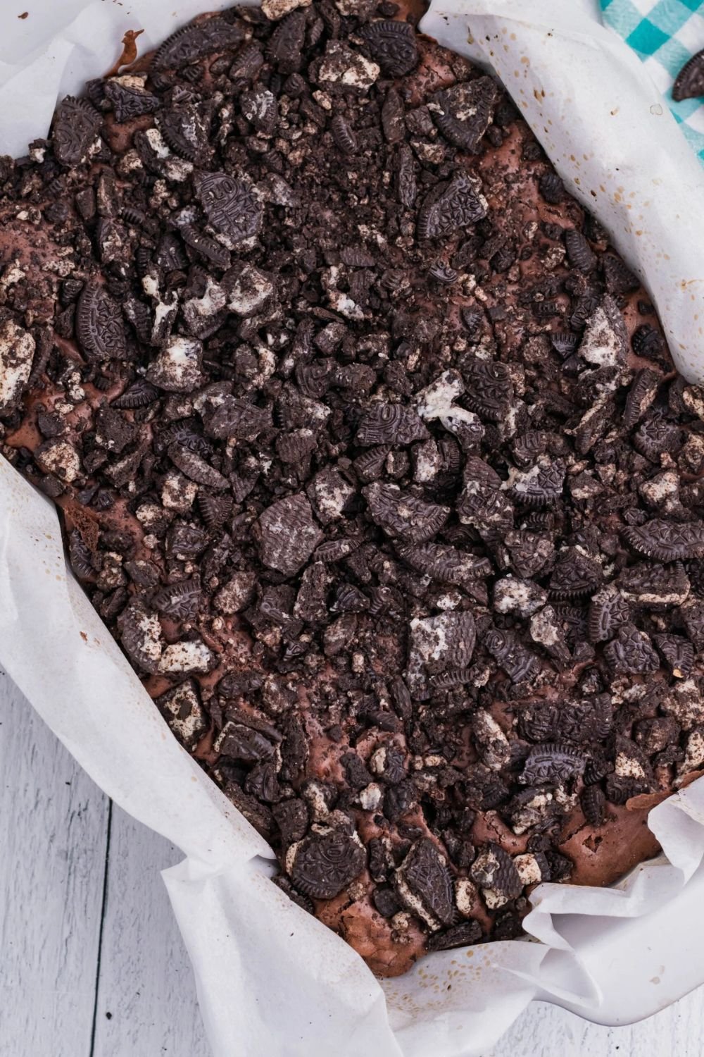 Oreo Stuffed Brownies in a pan with parchment paper sitting on table 