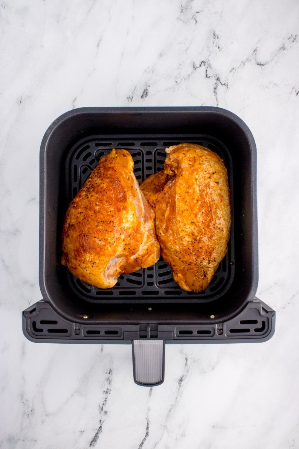 raw chicken in an air fryer basket on table for making Air Fryer Chicken Breast