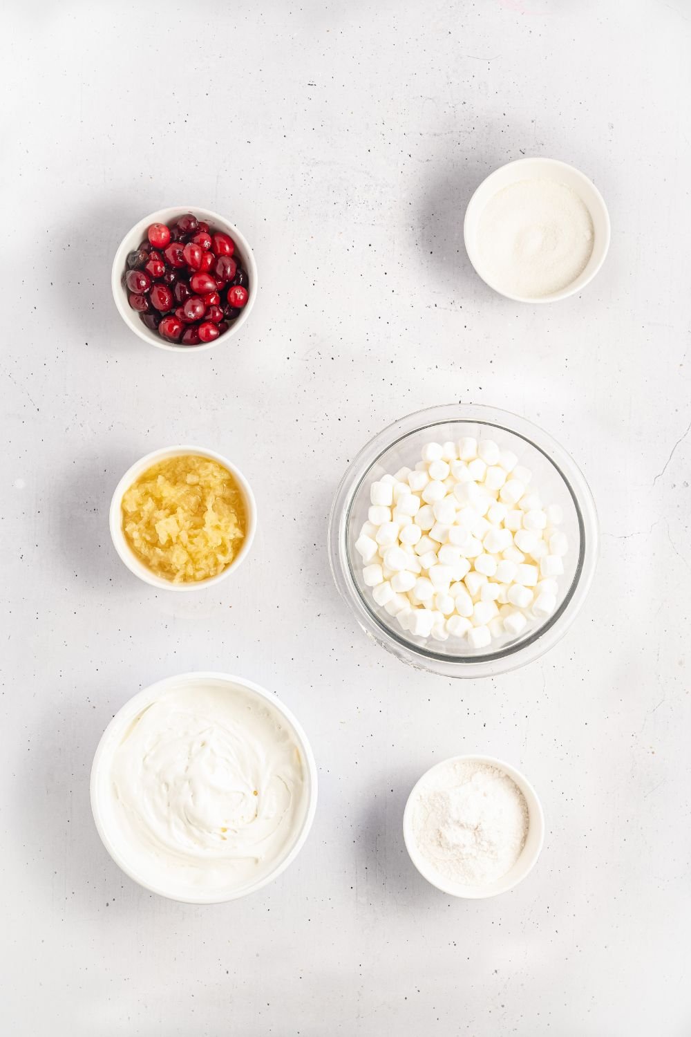 small bowls of ingredients for making Cranberry Fluff Salad. Cranberries, mini marshmallows, and more. 